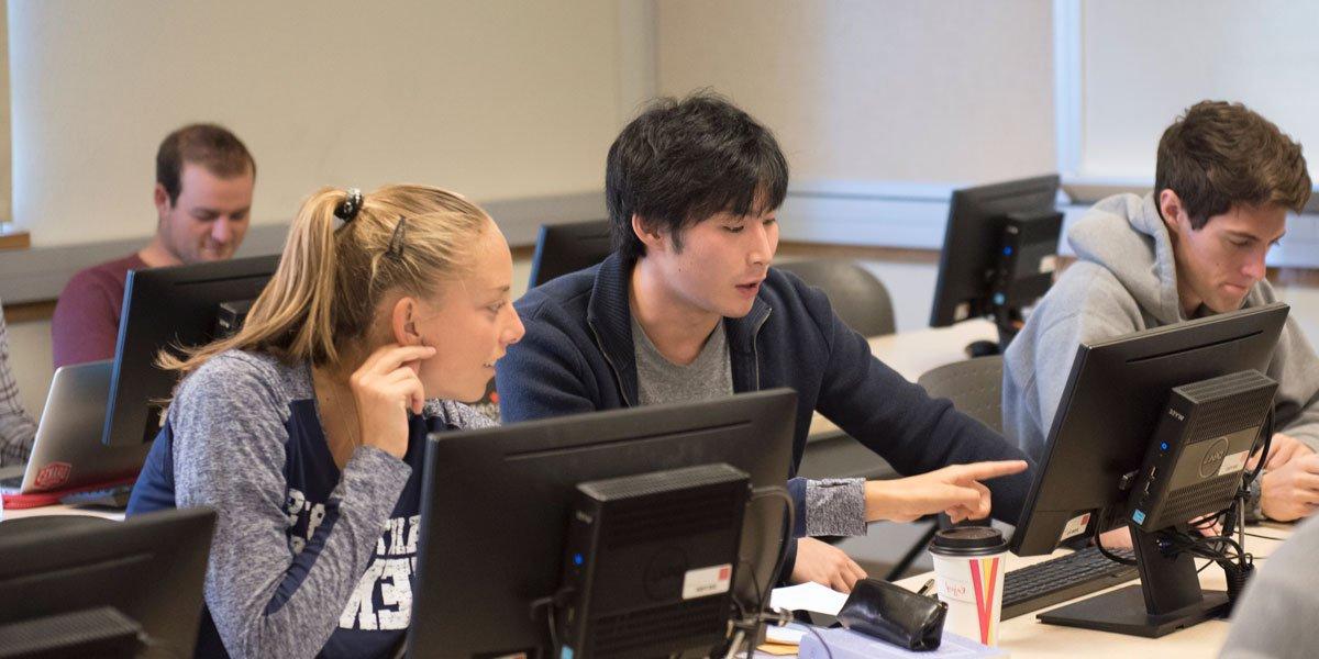 business analytics students pointing at data on screen