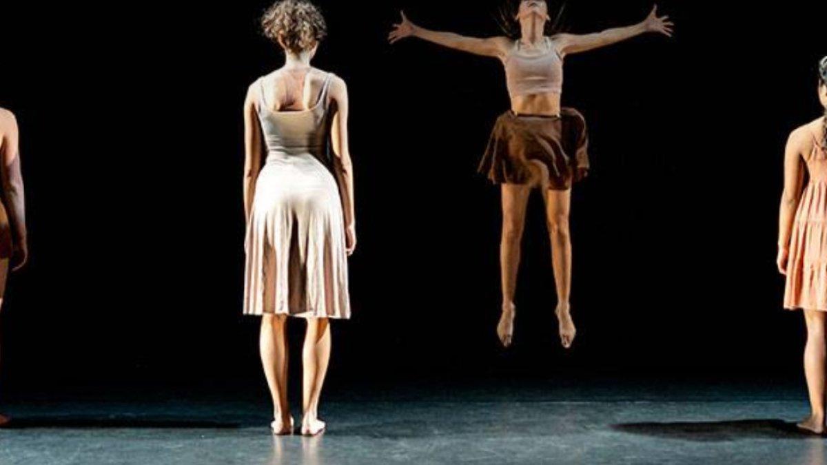 A group of dancers with their backs to the audience while the middle dancer jumps